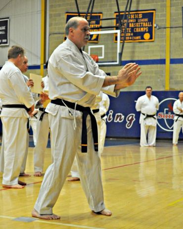 Karate instructor demonstrating a hand-block technique on a student.