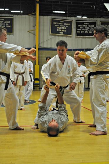 A group of martial artists in a drill, including a person on the floor.