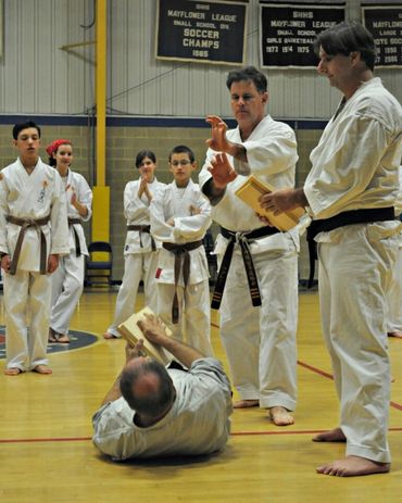 Karate instructor supervising a ground control and self-defense drill.