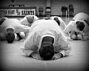 Karate student bowing face-down on the dojo floor.