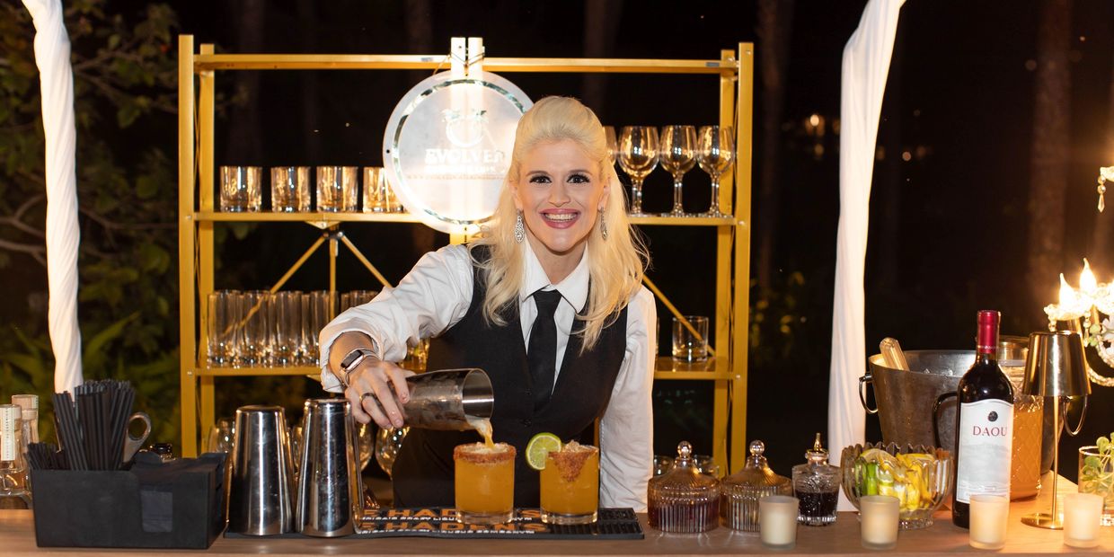 Bartender pouring drinks with a smile at a bar.
