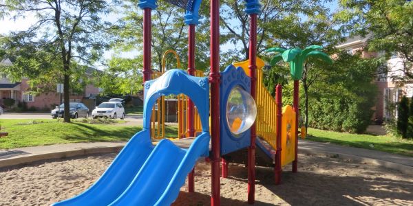 Colorful playground structure with blue slides in a sunny park.