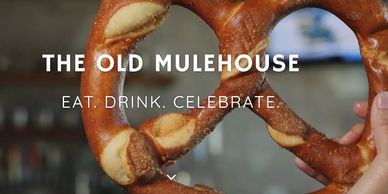 Hand holding a large pretzel with text promoting The Old Mulehouse.