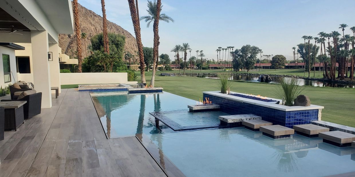 Modern outdoor pool with fire features and stepping stones overlooking a golf course.