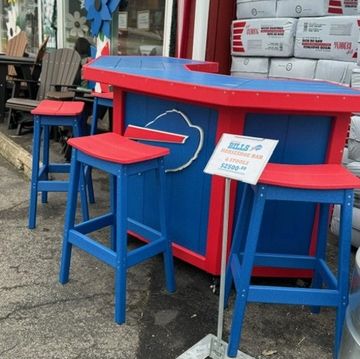 Blue and red outdoor bar setup with stools on pavement.