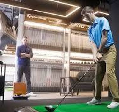 Two men practicing golf indoors.