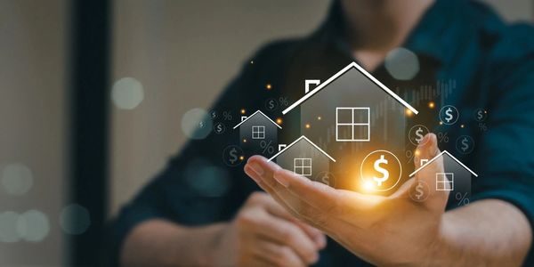 Hand holding glowing house icons symbolizing real estate investment.