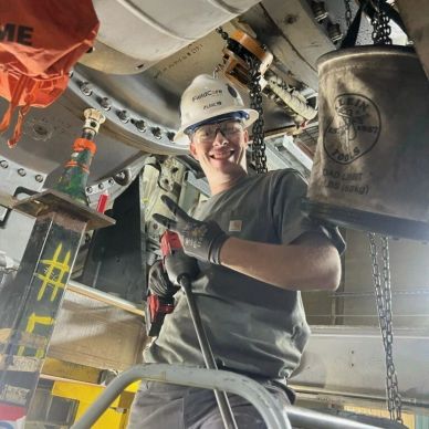 Smiling worker in safety gear holding a tool.