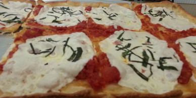 Close-up of rectangular pizza slices with white cheese and green herbs.