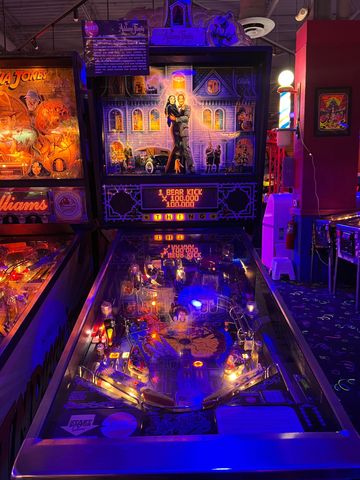 Pinball machine with spooky mansion theme lit in blue and purple.