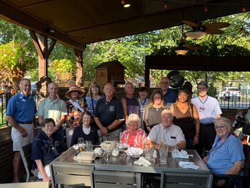 Group photo of people gathered outdoors under a covered patio.