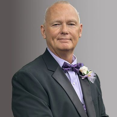 Elderly man in formal suit with bow tie and boutonniere.