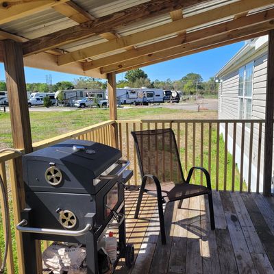 Covered porch with a grill and chair overlooking RVs.
