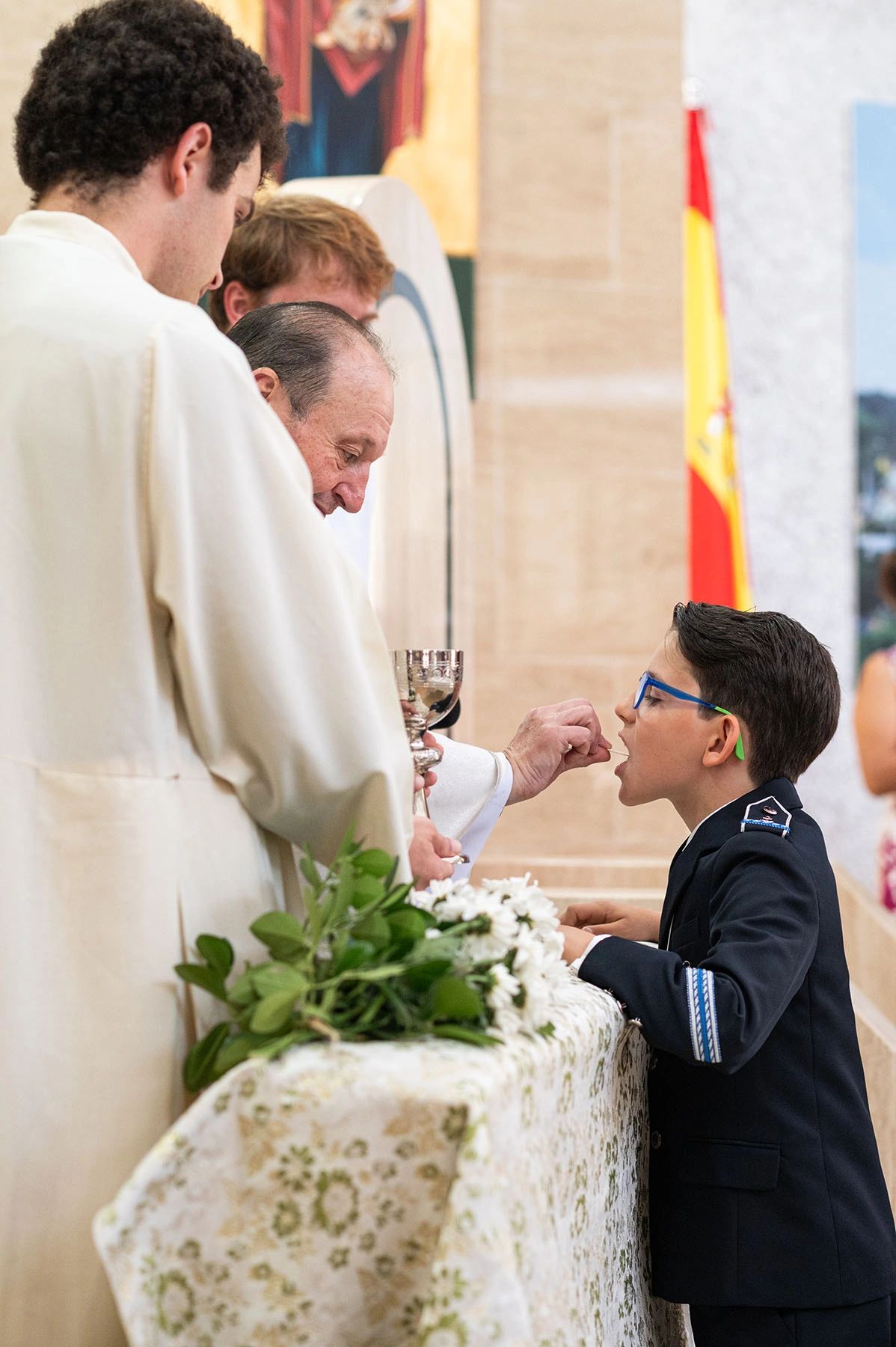 A boy receives communion from a priest during a religious ceremony.