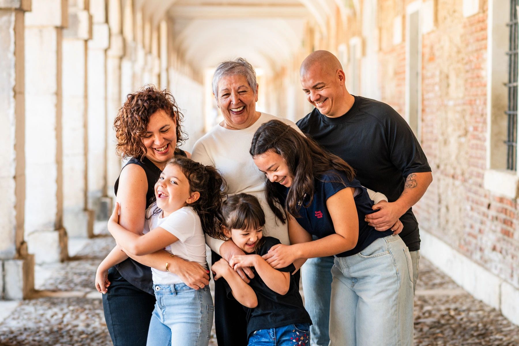 A joyful multi-generational family sharing a warm group hug outdoors.