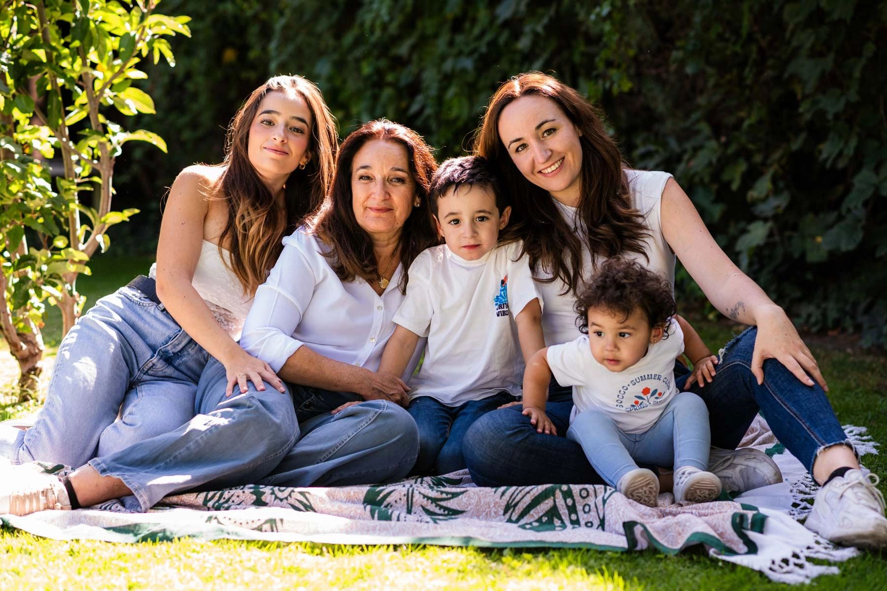 A multi-generational family enjoying a sunny day outdoors on a blanket.