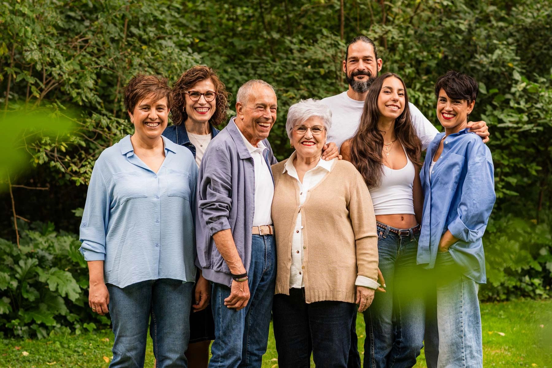 A happy multigenerational family posing outdoors in a garden.