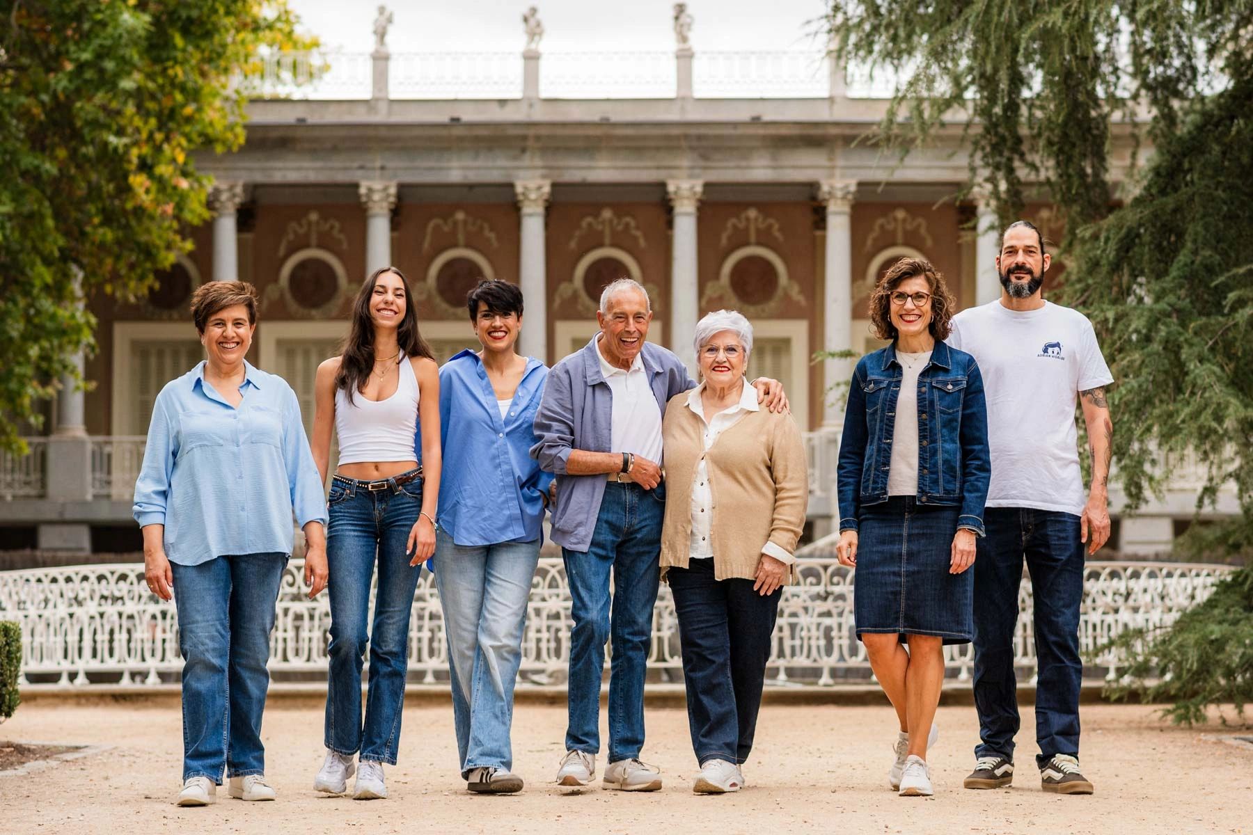 A diverse group of seven adults standing together outdoors in front of a historic building.
