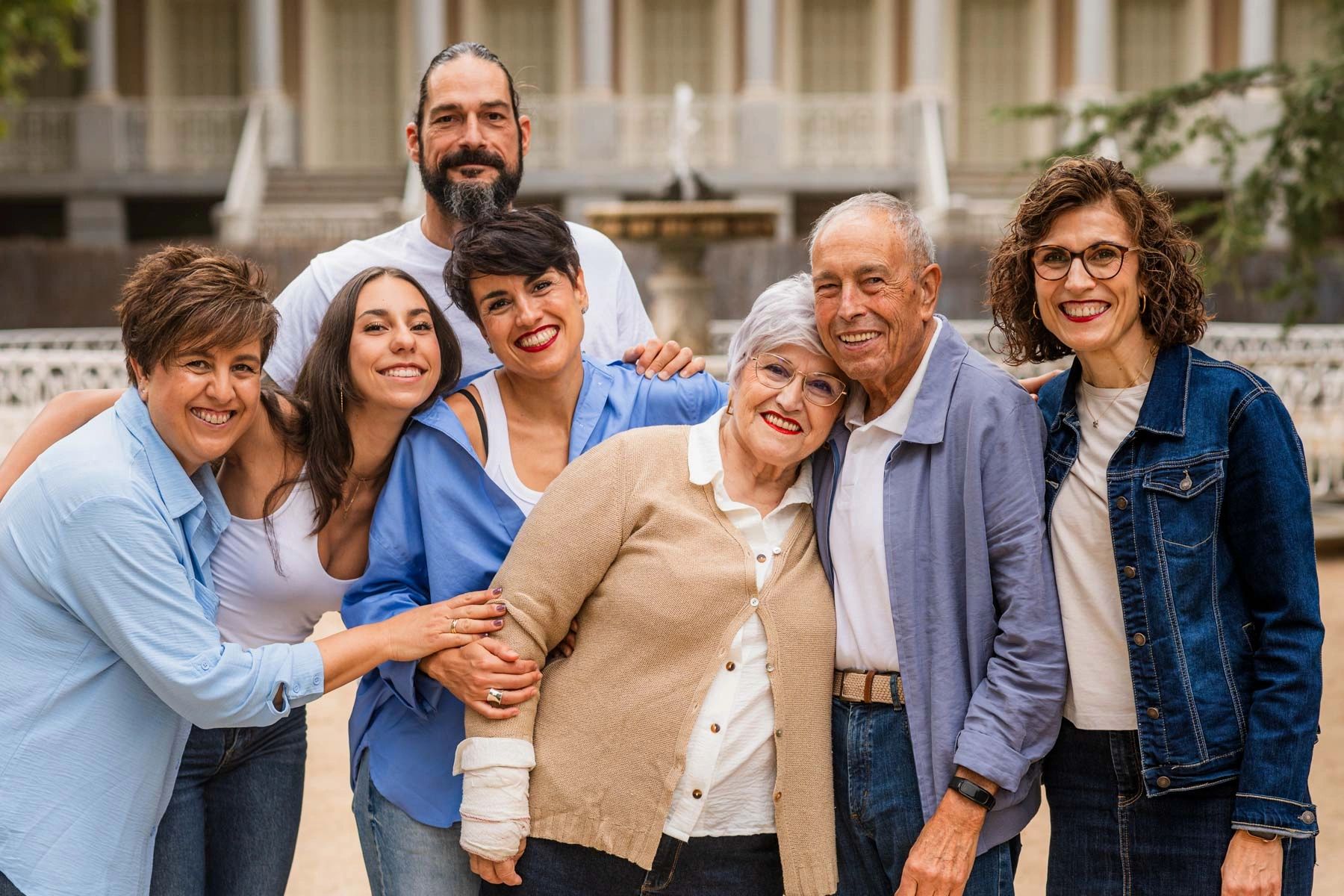 A joyful multi-generational family smiling together outdoors.