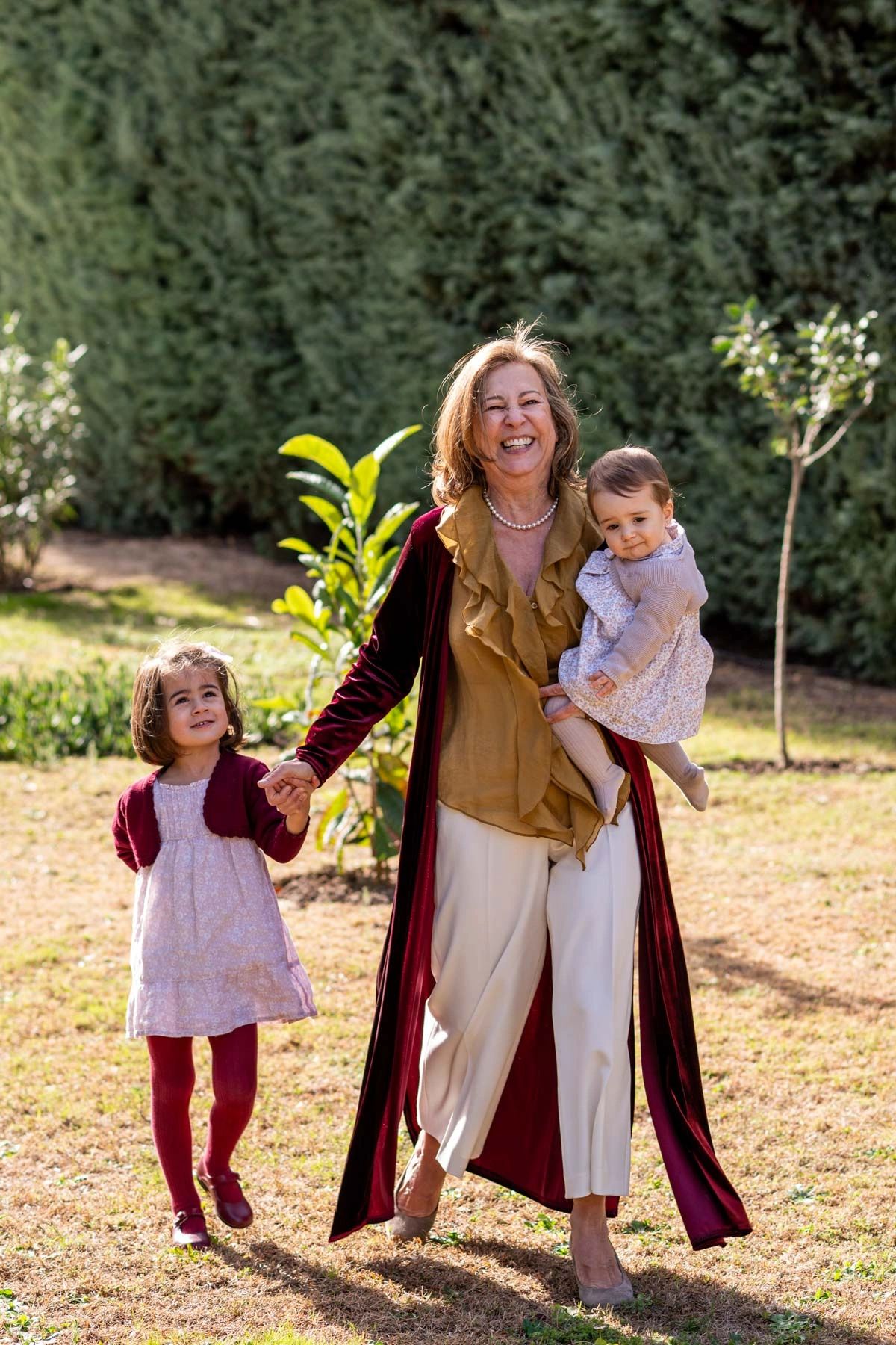 Happy grandmother walking outdoors with her two young granddaughters.
