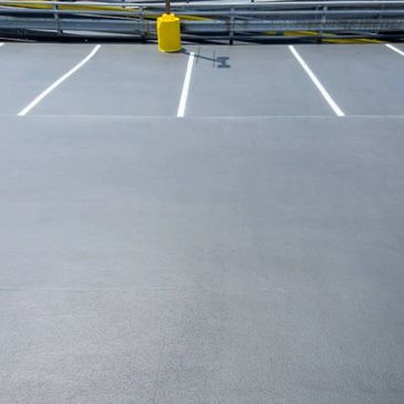 Empty parking lot with freshly painted lines and a yellow bollard.