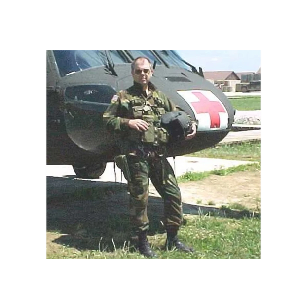 Military personnel standing in front of a medical helicopter holding a helmet.