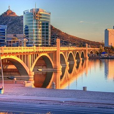Sunlit bridge over calm water at sunset.