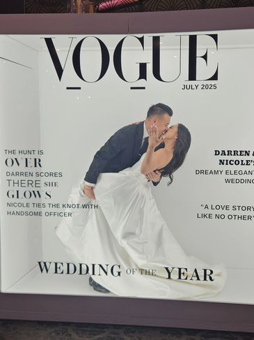 Couple poses in a Vogue-style wedding photo booth celebrating their elegant wedding.