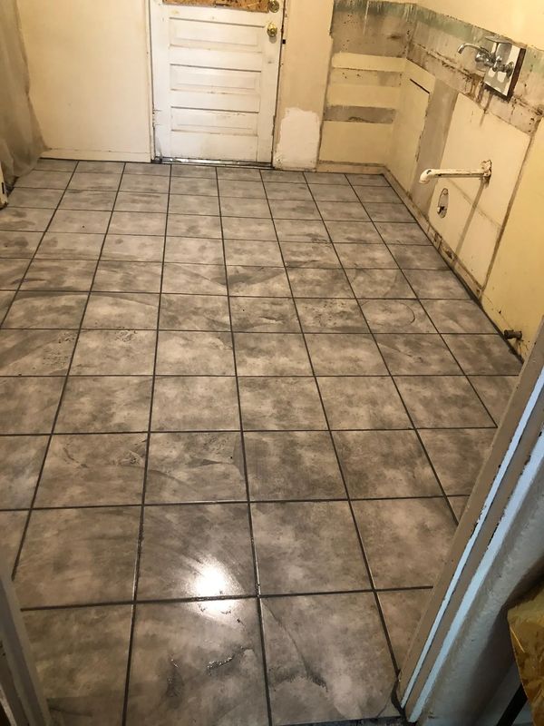 Newly installed gray tiled floor in an empty room with unfinished walls.