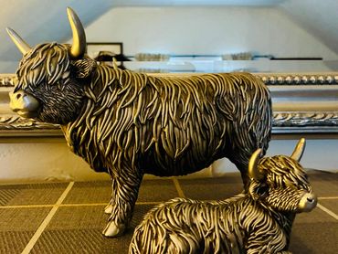 Two bronze Highland cow sculptures with detailed fur texture.