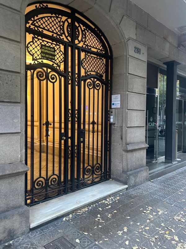 Elegant black wrought iron gate at building entrance with warm lighting inside.