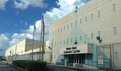 Exterior view of Metro West Detention Center with flags and clear sky.