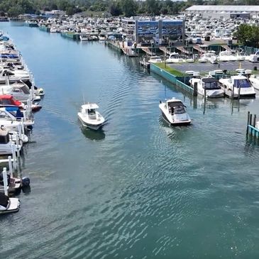 Two boats moving through a marina filled with docked boats.