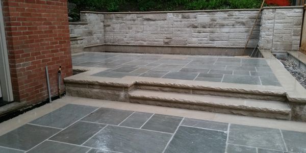 Flagstone, square cut with stone banding and steps. Stone wall in background.