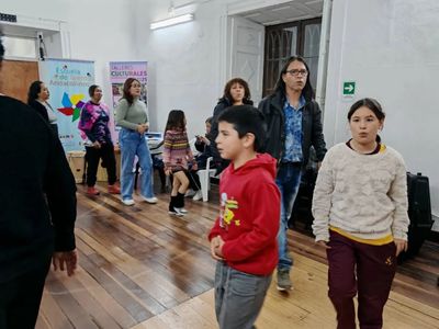 People of different ages gathered indoors, seemingly in a cultural or community event.