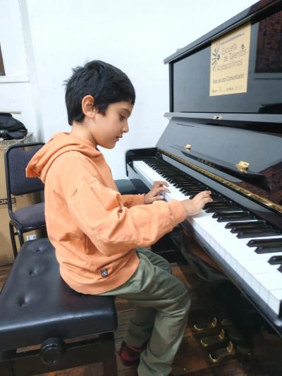 A young boy playing a black piano indoors.