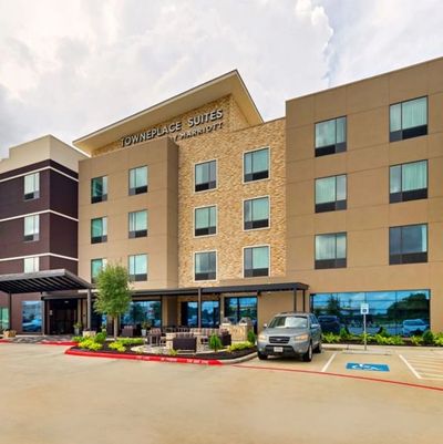 Exterior of TownePlace Suites by Marriott hotel with parking and seating area.