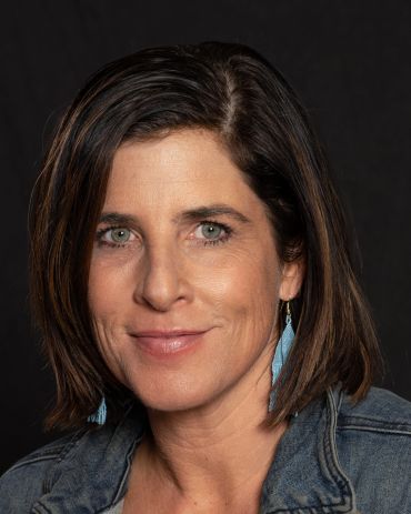 Woman with short brown hair and blue earrings.