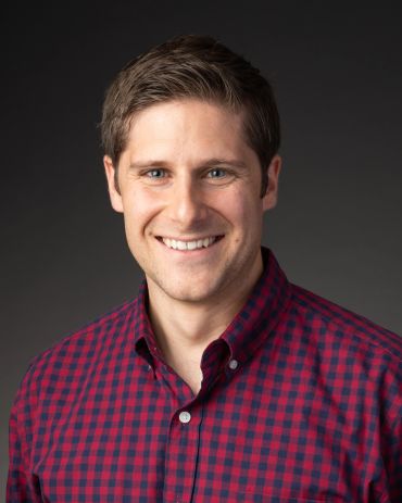 Smiling man in a red checkered shirt.