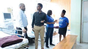 Four people engaged in discussion in a hospital room.