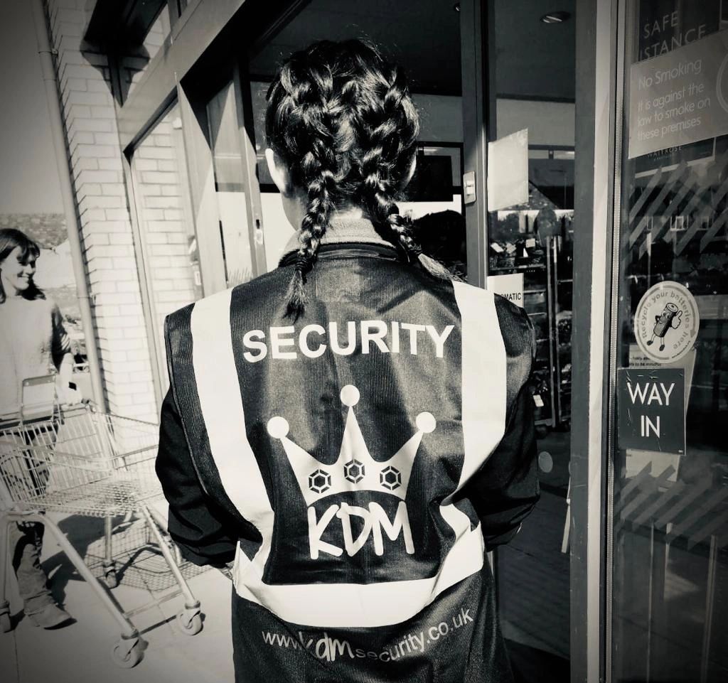 Security guard in black and white wearing a high visibility tactical vest with KDM Security branding