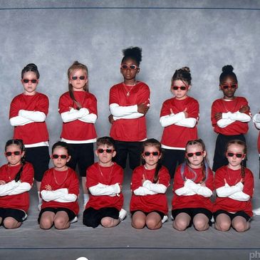 Une équipe d'enfants avec des lunettes de soleil et des tenues rouges.