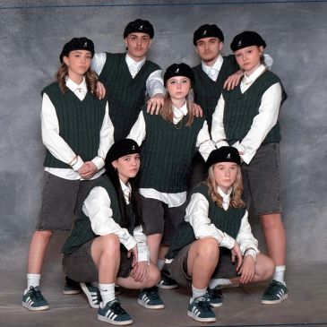 Groupe de jeunes en uniforme avec gilets verts et bérets noirs.