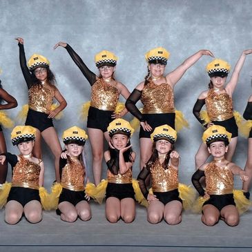 Groupe de jeunes danseuses en costume doré et chapeau jaune.