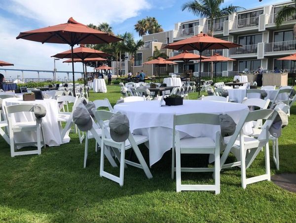 round table and white table cloths and resin chairs at the beach in san diego california