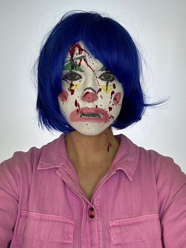 Woman with short blue hair and clown makeup