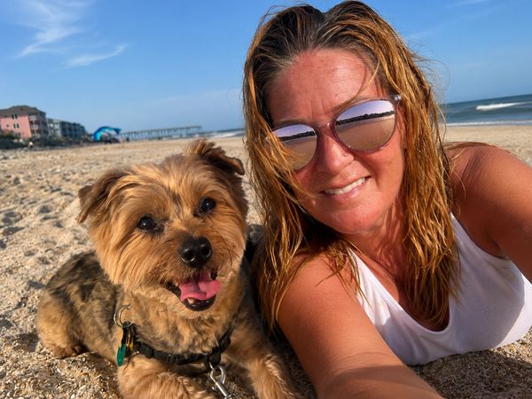 Woman and dog smiling at the beach.