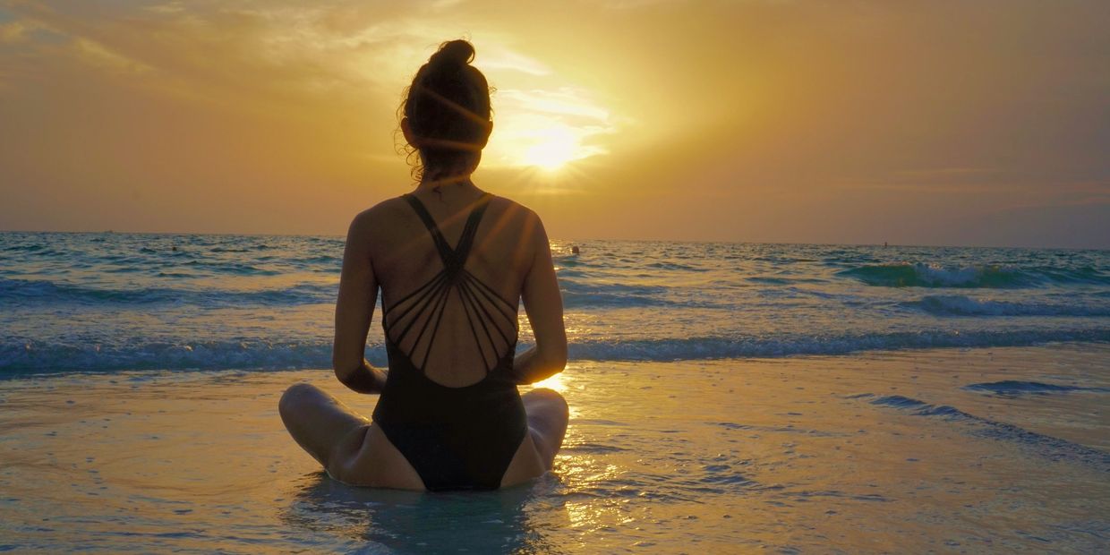 Woman enjoying sunset at Playa Guasacate, Nicaragua as part of a wellness retreat ocean excursion.