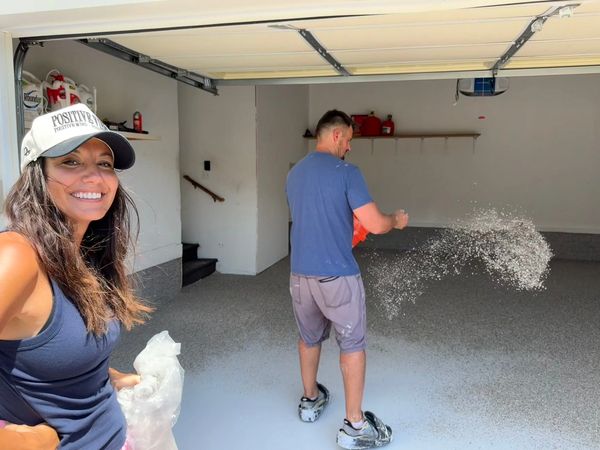 Couple working on garage floor coating with smiles.