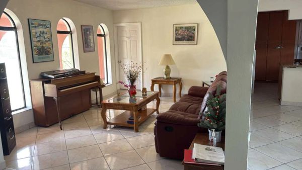 Cozy living room with piano and brown sofa.